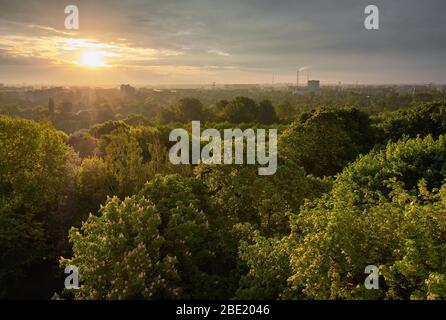 Paesaggio urbano con vista sul verde del parco e tubi industriali sullo skyline. Foto Stock