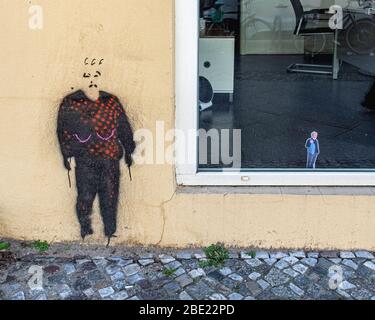 Fai shopping in Brunnenstrasse con l'uomo dell'arte di strada e un piccolo incolla maschile in vetrina. Chiuso durante la pandemia del virus Corona. Concetto di distanza sociale Foto Stock