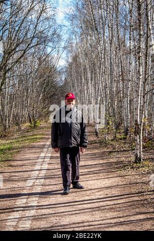 Berlino, Mitte, COVID-19 epidemia. Solitario uomo anziano cammina su sentiero vuoto in legno di betulla nel parco Nordbahnhof durante la pandemia COVID-19 Foto Stock