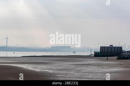 Un uomo cammina i suoi cani sulla spiaggia di New Brighton vicino a Liverpool mentre il Regno Unito continua a bloccare per contribuire a frenare la diffusione del coronavirus. Foto Stock