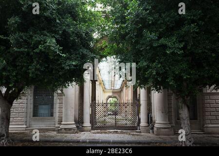 Colonna incorniciata antica strada ingresso cancello arco che è chiuso circondato da alberi Foto Stock