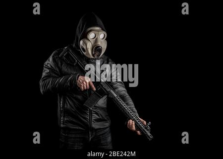 Un uomo in maschera a gas con una pistola in mano su sfondo nero. Un combattente in una maschera a gas è pronto per la battaglia. Foto Stock