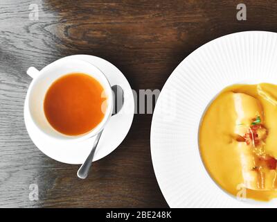 Tazza di sano tè alle erbe con mare-spina di buckitorn, zenzero e miele e zuppa di crema di zucca su un tavolo di legno chiaro testurizzato in un caffè con moderno alla moda Foto Stock