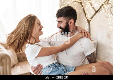 Immagine di un uomo romantico con bearded che porta la donna in mano e che sorride in una stanza luminosa a casa Foto Stock