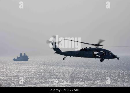 200408-N-MH210-1056 GOLFO ARABICO (8 aprile 2020) - un MH-60S Seahawk attaccato alle Dagon Whales di elicottero Sea Combat Squadron (HSC) 28 si avvicina alla nave di carico secco e munizioni USNS William McLean (T-AKE 12) durante un rifornimento verticale con la nave d'assalto anfibia USS Bataan (LHD 5), Con la nave di trasporto USS New York (LPD 21) sullo sfondo, 8 aprile 2020. Bataan è il fiore all'occhiello del Bataan Amphibious Ready Group e, con la 26a unità navale imbarcata, viene distribuito nell'area della 5th Fleet statunitense per operazioni a supporto di operazioni navali per garantire ma Foto Stock