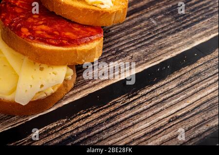 Toast di grano fresco con burro, salsiccia e formaggio, un piatto di burro  di legno con un pezzo di burro e una tazza di tè su sfondo ligneo. Primo  piano Foto stock 