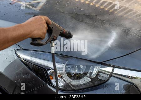 Autolavaggio manuale con acqua pressurizzata. Pulizia della parte anteriore dell'auto con acqua ad alta pressione. Foto Stock