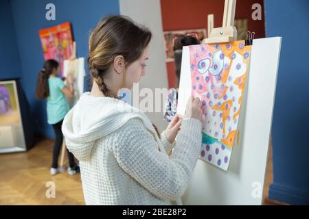 Baku, Azerbaigian. 14.05.2019 . Bambini in pittura bianca con spazzola su cavalletto. Le ragazze stanno dipingendo alla mostra. Museo centro espositivo sala . Foto Stock