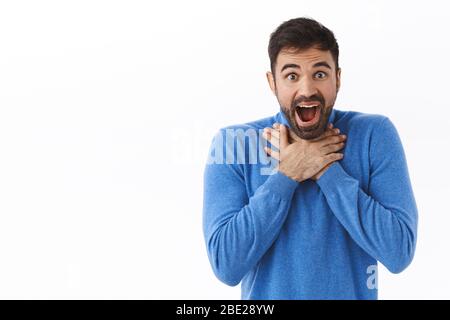 Ritratto di speechless, impressionato bell'uomo, perdere il suo discorso, gasping e bocca aperta stupito, sorridente divertito, tenere le mani sul petto stupito, cant Foto Stock