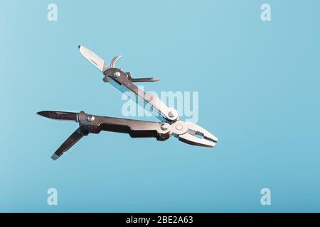 Lo strumento multifunzione multitool si trova su uno sfondo blu. Il concetto di un multi-utensile espanso con spazio libero. Foto Stock