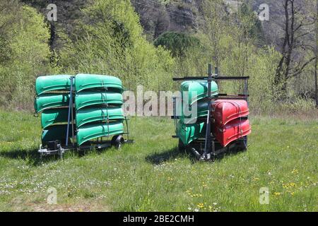 Canoe verdi e rosse impilate su due rimorchi Foto Stock