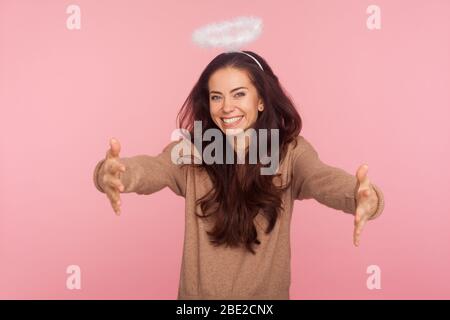 Gentilezza e generosità angelica. Ritratto di bella giovane donna con alone sopra la testa tenendo mani allungate e sorridente, dando libero abbracci, invi Foto Stock