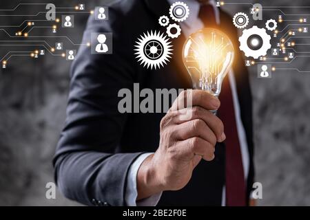 Innovazione e idea di azienda leader professionale che detiene lampadina di illuminazione, gestione di pensiero e potenza del concetto tecnologico Foto Stock