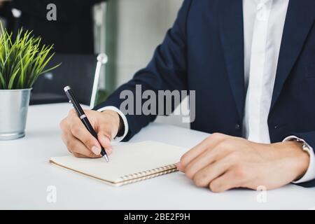 uomo d'affari che scrive e memoria sul notebook come riunione Foto Stock