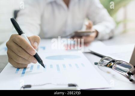 uomo d'affari o banchiere che controlla il grafico di finanza di profitto sulla tabella Foto Stock