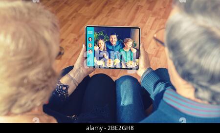 Coppia senior che parla in videochiamata con figlio e nipoti a causa della quarantena isolamento casa Foto Stock