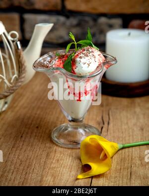 gelato alla vaniglia con sciroppo di fragola guarnito con cioccolato grattugiato Foto Stock