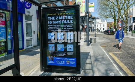 Watford, Regno Unito. 11 aprile 2020. Uno schermo pubblicitario su un rifugio fermata autobus nel centro commerciale di Watford il Sabato di Pasqua durante il blocco come il coronavirus (COVID19) pandemia continua. La schermata mostra un messaggio che promuove il 2 metri, regola per NHS. Credit: Stephen Chung / Alamy Live News Foto Stock