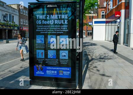 Watford, Regno Unito. 11 aprile 2020. Uno schermo pubblicitario su un rifugio fermata autobus nel centro commerciale di Watford il Sabato di Pasqua durante il blocco come il coronavirus (COVID19) pandemia continua. La schermata mostra un messaggio che promuove il 2 metri, regola per NHS. Credit: Stephen Chung / Alamy Live News Foto Stock