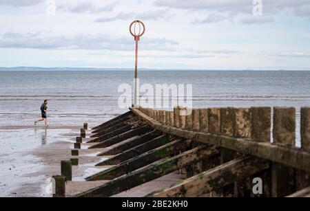 Portobello, Edimburgo. Scozia, Regno Unito. 11 aprile 2020. Il fine settimana di Pasqua sabato mattina il pubblico era all'aperto, esercitandosi e camminando sulla spiaggia di Portobello fuori di Edimburgo. La spiaggia e il lungomare erano molto tranquilli e la gente si stava esercitando a distanza sociale. Iain Masterton/Alamy Live News Foto Stock