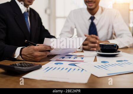 Manager che controlla la documentazione finanziaria, business expert pianificazione sulla crescita degli investimenti e il profitto annuale con businessman on desk in offi Foto Stock