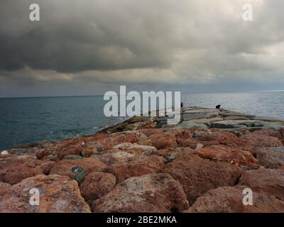 Fisherman lungo il molo in pietra a Varazze, Genova Italia Foto Stock