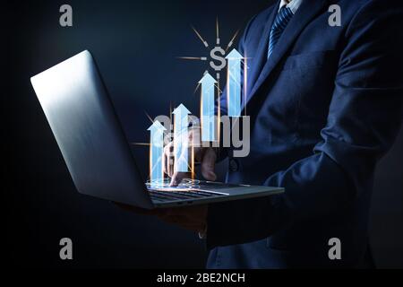 business e tecnologia di stampa businessman su laptop con freccia su e icona denaro, ottenere profitto e finanza di successo da elettronica Foto Stock