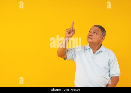 Ritratto di vecchio uomo che punta su sfondo giallo, introdurre produzione su spazio copia e presente pensiero concetto Foto Stock