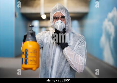 Un uomo disinfetta gli spazi pubblici al momento della crisi della corona Foto Stock