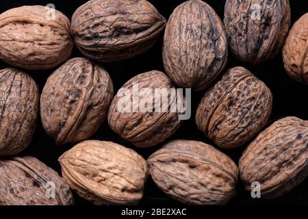 un'immagine fantastica e originale di wallnut su un piatto nero su sfondo nero scuro, vista dall'alto, dettagli Foto Stock