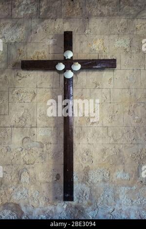 Croce di legno con piccole conchiglie di capesante sulla parete della Collegiale de la Romieu. Foto Stock