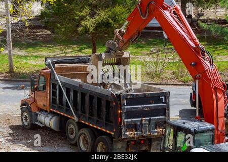 L'escavatore preleva i rifiuti da costruzione per caricarli su un dumper Foto Stock