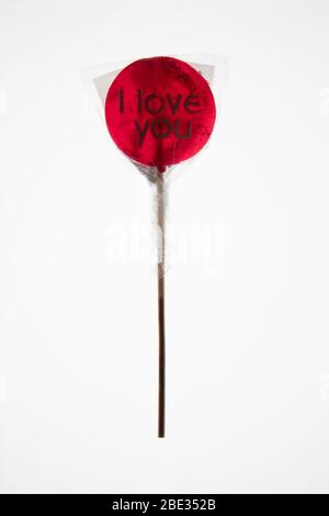 Un lecca di lollypop rosso trasparente avvolto con un'ottima vista su sfondo bianco, piatto e dall'alto Foto Stock