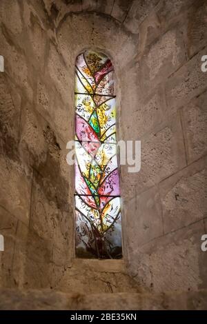 Finestra di vetro colorato decorata nella piccola chiesa nel villaggio fortificato di Larressingle, Francia. Foto Stock