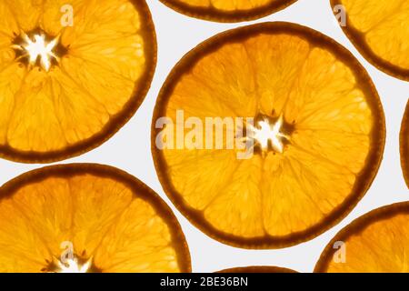 un interessante schema di primo piano di una foto di fette arancioni trasparenti su uno sfondo bianco brillante Foto Stock