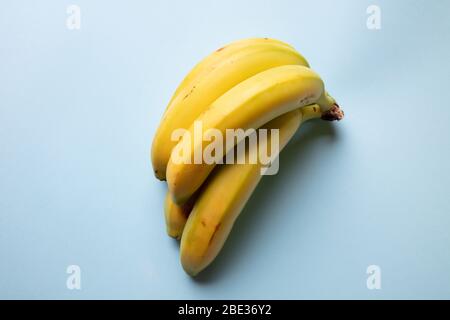 una vista fresca di un mazzo di banane gialle poggiate su un sfondo blu chiaro pastello, vista dall'alto Foto Stock