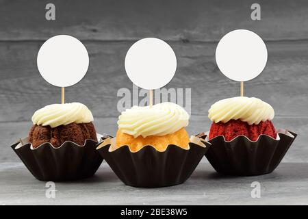 Tre invitanti cupcake gourmet su una superficie di marmo grigio con top di cupcake rotondi. Foto Stock