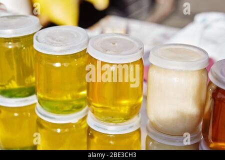 Diverse varietà di miele dolce dorato e bianco al mercato contadino. Miele naturale in vari vasi Foto Stock