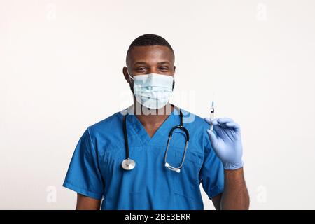 Medico nero con maschera facciale e guanti per l'iniezione Foto Stock