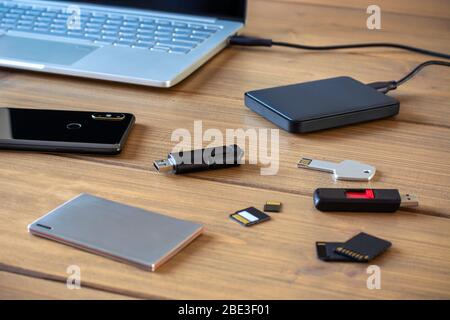 Vari dispositivi di memorizzazione dati digitali. Chiavette USB, disco rigido esterno, schede SD, schede mini e micro SD, computer portatile e smartphone Foto Stock