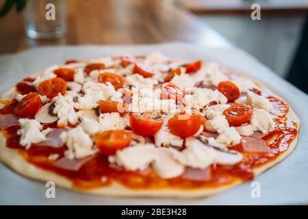 Primo piano di una pizza italiana tradizionale fatta in casa margherita. Preparazione classica pizza italiana su piano di lavoro in legno Foto Stock