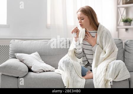 Giovane donna che tossisce appena a casa, spazio libero Foto Stock