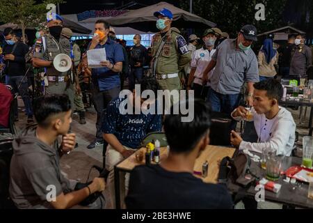 Lhokseumawe, Aceh, Indonesia. 11 Aprile 2020. Un gruppo militare e di polizia indonesiano congiunto con il governo pattuglia un affollato bar che non applicava regole di distanza sociale tra i timori di un Coronavirus COVID-19 a Lhokseumawe. Il governo ha sanzionato e revocato le licenze di alcuni bar che violavano le normative locali. Credit: Zikri Maulana/ZUMA Wire/Alamy Live News Foto Stock