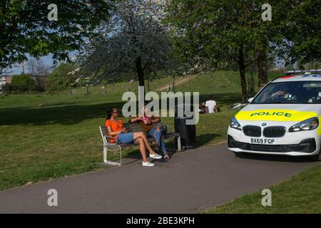 Londra UK 11 aprile 2020 la polizia guida un'auto di pattuglia intorno al parco Burgess urgeing la gente per andare a casa come la diffusione della malattia di coronavirus (Covid-19) continua. Foto Stock