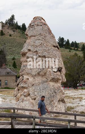 YELLOWSTONE NATIONAL PARK, USA - 14 2014 luglio: Un uomo che cammina davanti al cono dormiente delle sorgenti termali di Liberty Cap nel Parco Nazionale di Yellowstone, Wyoming. Foto Stock