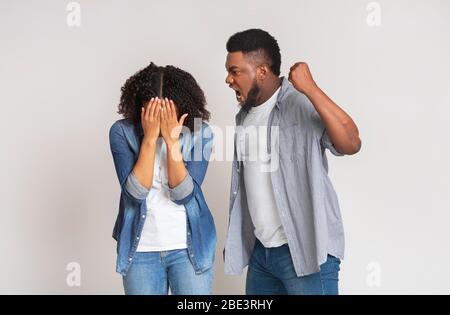 Violenza domestica. Arrabbiato uomo nero minacciando la sua ragazza con pugno Foto Stock