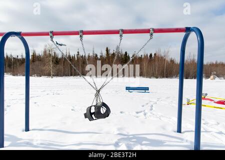 Allacciato swing set in chiuso parco giochi durante coronavirus COVID-19 pandemic, Yellowknife, Northwest Territories, Canada, inverno, 10 aprile 2020 Foto Stock