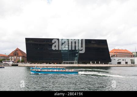 Due barche passano davanti alla Biblioteca reale (Kongelige Bibliotek), conosciuta come il diamante Nero, nel centro di Copenhagen, Danimarca. Foto Stock