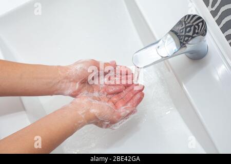 Lavaggio delle mani. Una donna usa il sapone e lava le mani sotto il rubinetto. Concetto di igiene. Primo piano Foto Stock