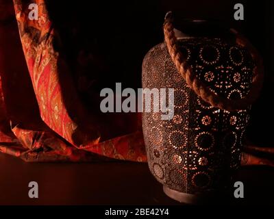 Lanterna araba vicino a un tessuto rosso orientale su uno sfondo di legno marrone.lampada Eid o lanterna per Ramadan e altre vacanze islamiche musulmane, con copia Foto Stock